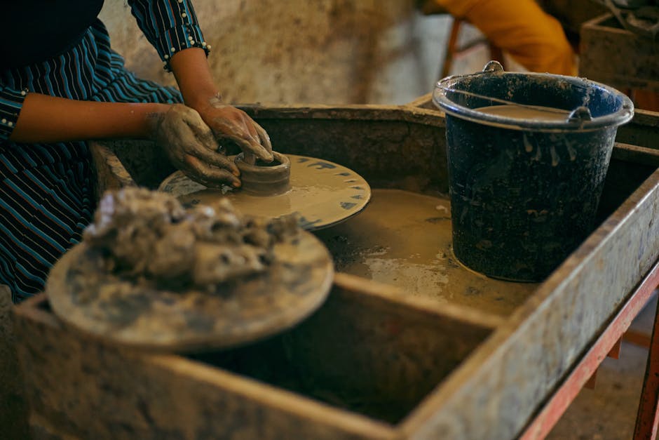 Close-up of hands creating pottery with clay on a spinning wheel in an artisanal workshop.