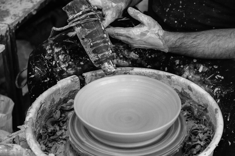 Artisan uses a heat tool to shape pottery on a spinning wheel in a studio.